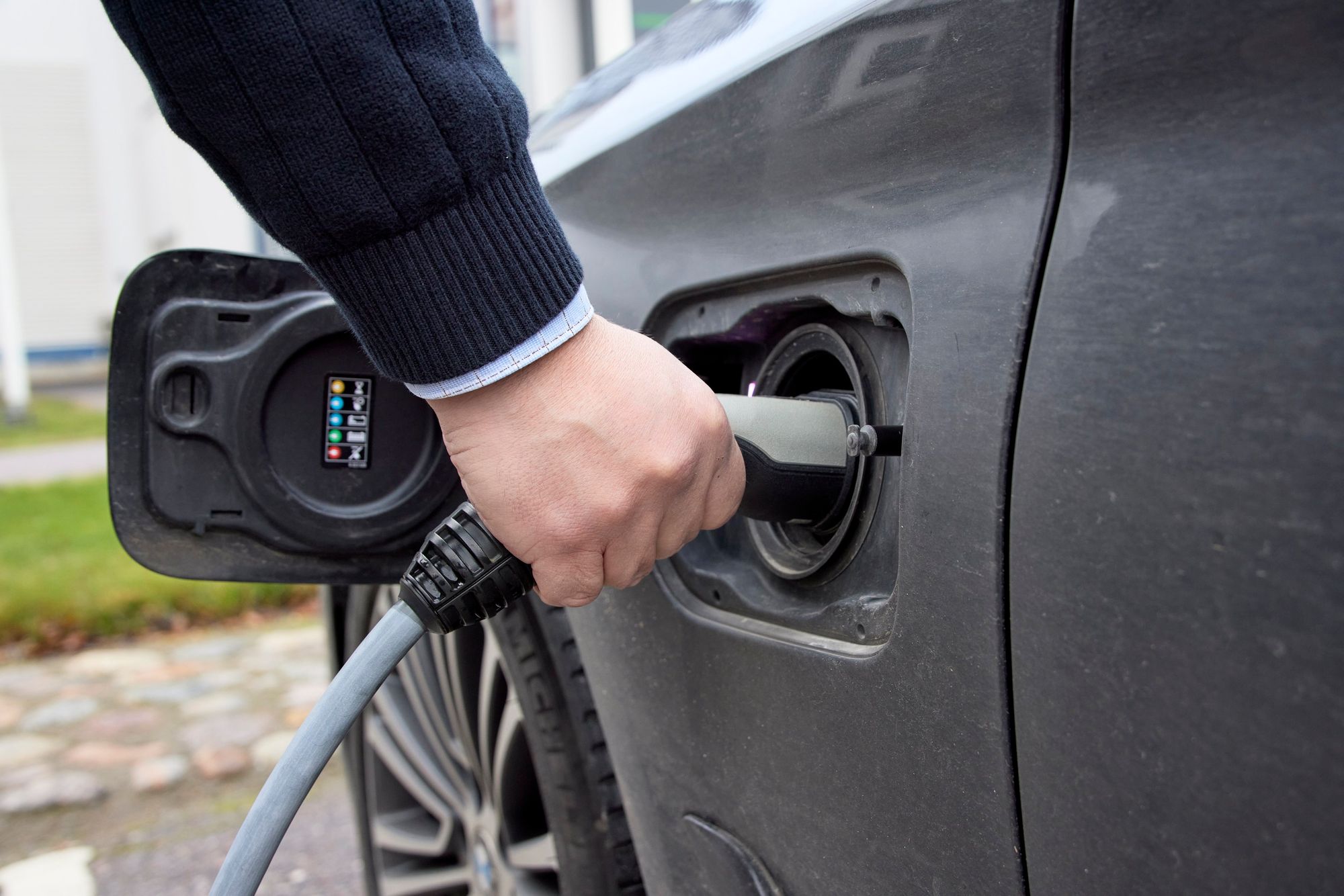 Person holding electric vehicle charger connected to car