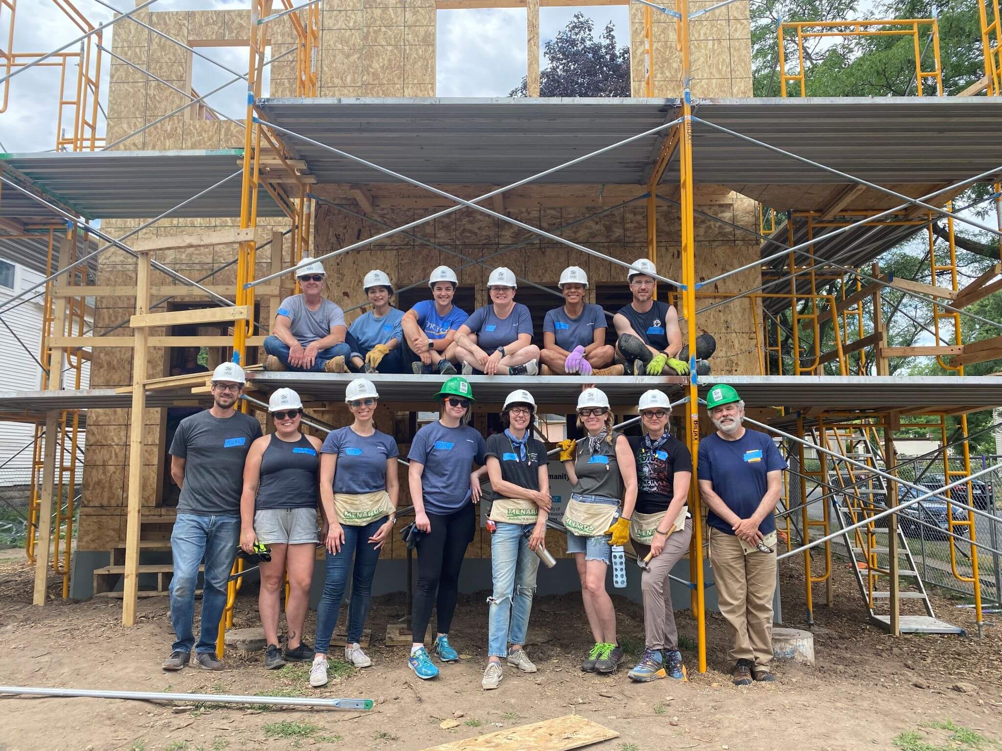 Volunteers posing in front of photo while working on a house