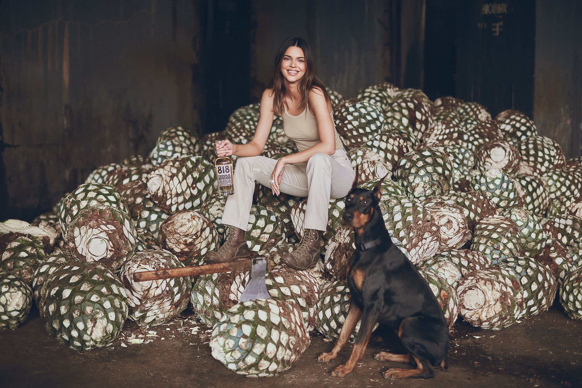 Kendall Jenner sitting on agave holding 818 tequila bottle