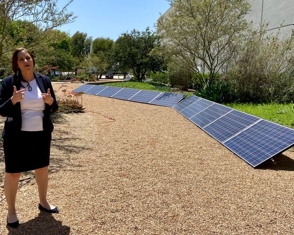 Kelly Vlahakis-Hanks, president and CEO of Ecos, talking outside in front of solar panels